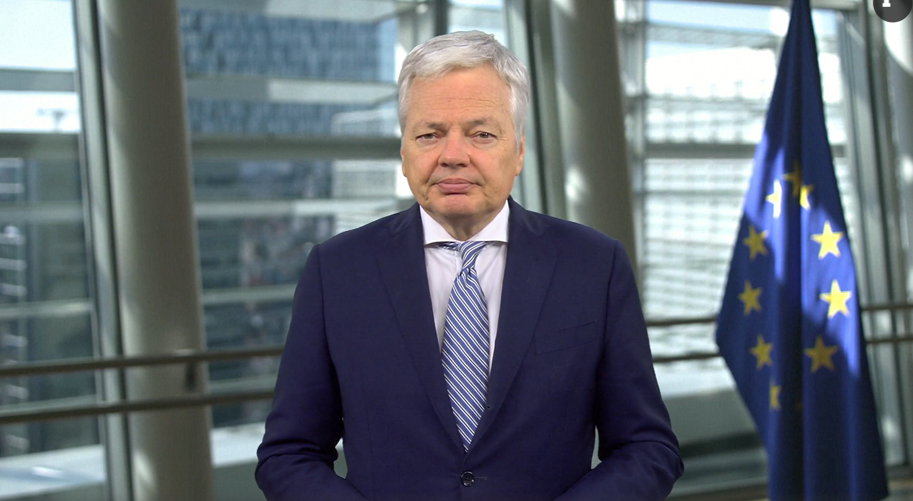 Didier Reynders, EU Commissioner of Justice, standing in front of an EU flag
